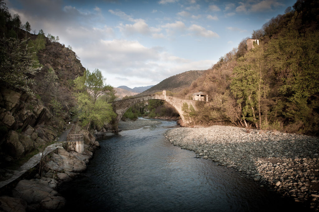 Medieval stone bridge in wooded area over river